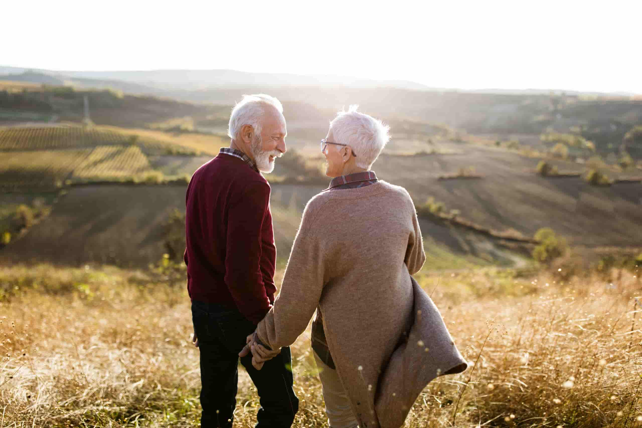 Back view of happy senior couple walking down the hill.